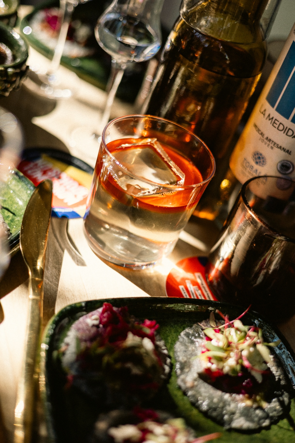 Artisanal Mexican whisky cocktail served in a crystal rocks glass with handcrafted antojitos in a Roma Norte tasting room by Onedaytrip Mexico City